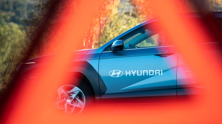 Durch ein unscharfes Warndreieck hindurch: der Hyundai-Schriftzug an der Fahrzeugflanke