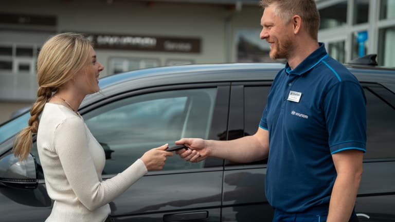 Ein Mitarbeiter übergibt einer Kundin den Schlüssel ihres neuen Hyundai