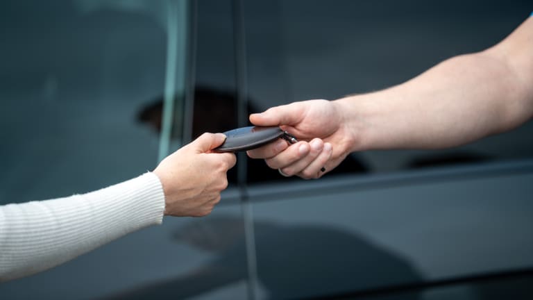 Schlüsselübergabe: Eine Hand reicht den Fahrzeugschlüssel weiter